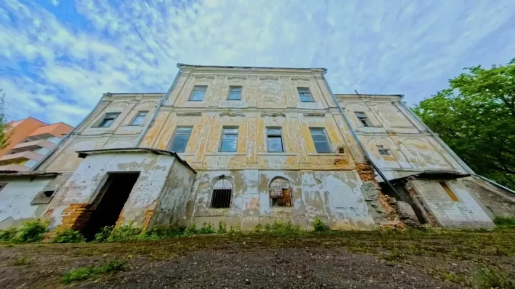 Fachada deteriorada del palacio barroco de ladrillo rojo comprado por 28€, con ventanas rotas y vegetación creciendo en las grietas