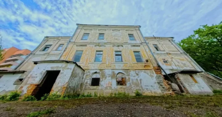 Fachada deteriorada del palacio barroco de ladrillo rojo comprado por 28€, con ventanas rotas y vegetación creciendo en las grietas