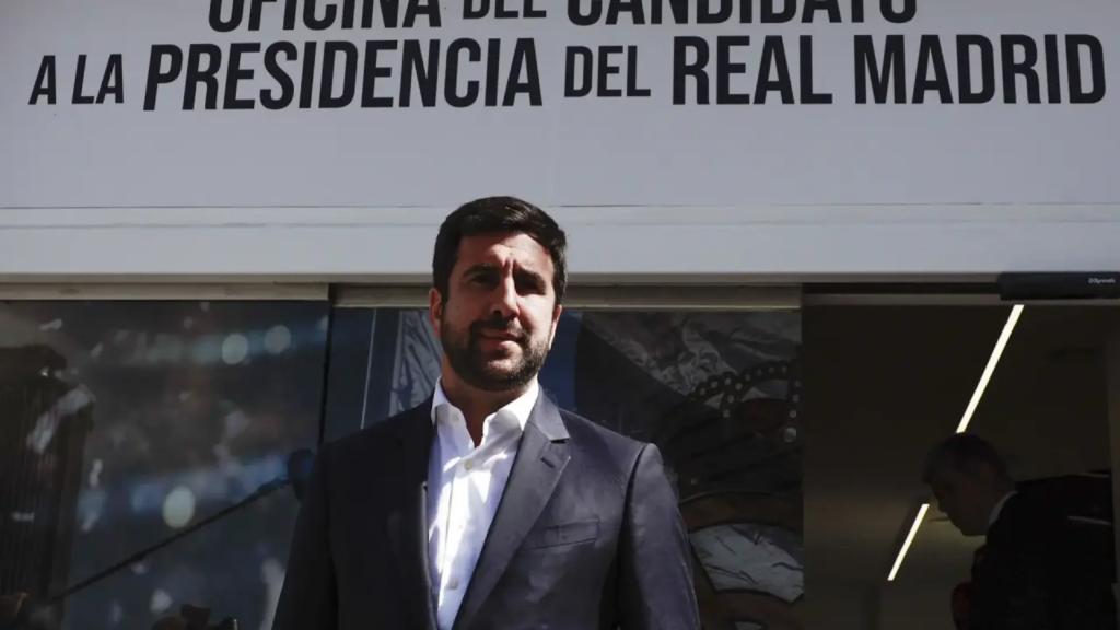 Enrique Riquelme señala el Bernabéu desde su sede electoral en Castellana, con carteles de 'Democracia ya' y socios a sus espaldas