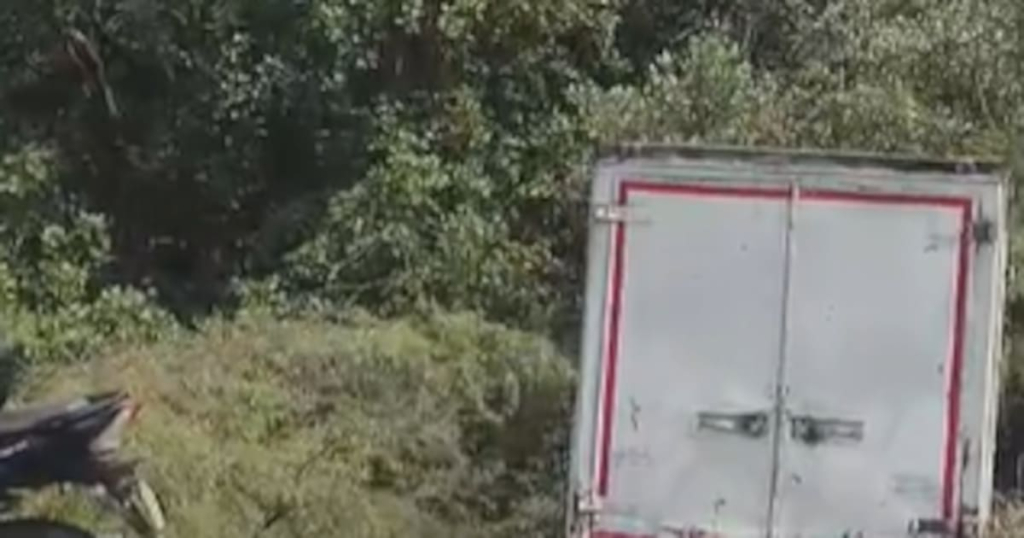Furgón destrozado y restos de motocicleta esparcidos en el asfalto tras choque frontal en la Troncal del Caribe km 25