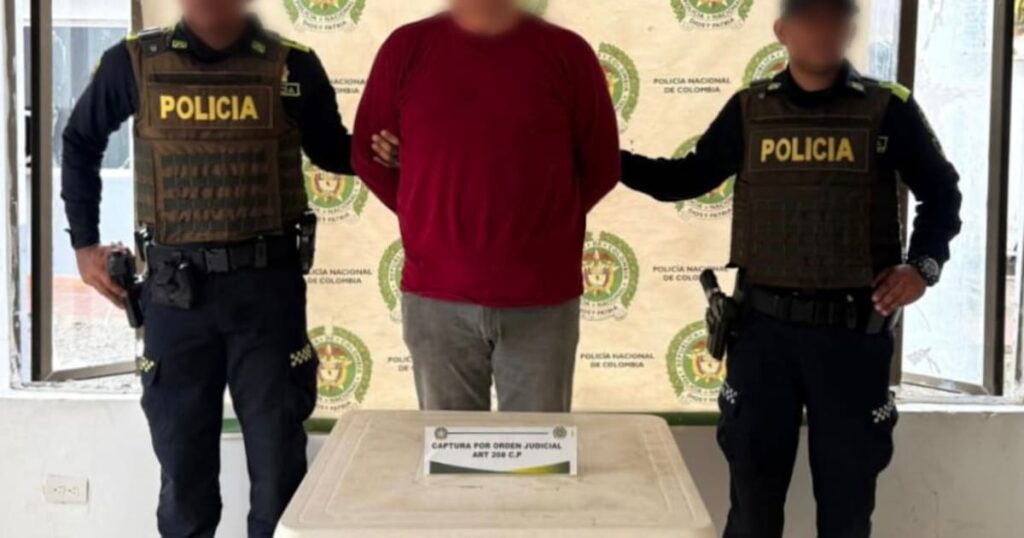Imagen de un agente de policía llevando a un hombre esposado. El hombre es un presunto abusador de una menor.