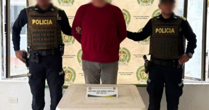 Imagen de un agente de policía llevando a un hombre esposado. El hombre es un presunto abusador de una menor.