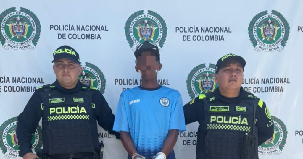 Imagen de un policía llevando a un detenido, tras la captura del homicida de un técnico de celulares