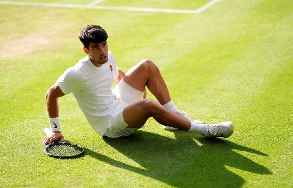 Imagen de Carlos Alcaraz en una pista de tenis con una mueca de dolor en su rostro
