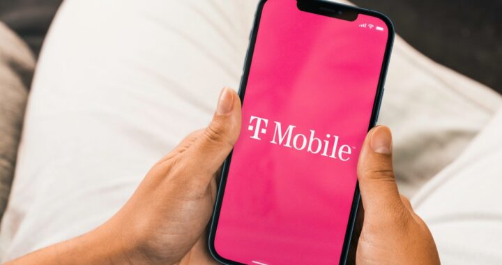 Una mano sostiene un smartphone con una tarjeta eSIM en la pantalla, con un estadio de fútbol al fondo