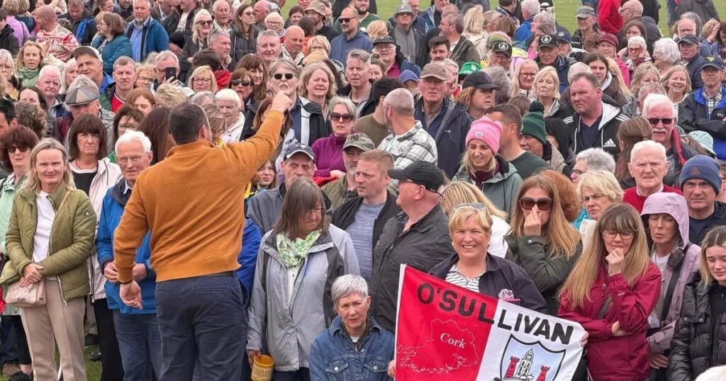 Multitud de personas con el apellido O’Sullivan celebrando el récord Guinness en un pueblo irlandés con banderas y sonrisas