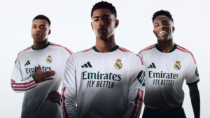Primera camiseta rosa y verde del Real Madrid 2026-2027 con detalles geométricos inspirados en su escudo, sobre maniquí en el Bernabéu