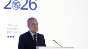 Florentino Pérez en mitin electoral señalando con gesto serio, fondo con escudo del Real Madrid