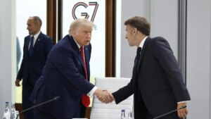 Donald Trump en un discurso firme con gesto serio, fondo de bandera estadounidense