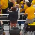 Dos aficionados colombianos en silla de ruedas de pie celebrando un gol en el Mundial