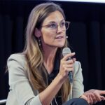 Cathie Wood en evento analizando gráficos de Palantir, Cerebras y Coinbase