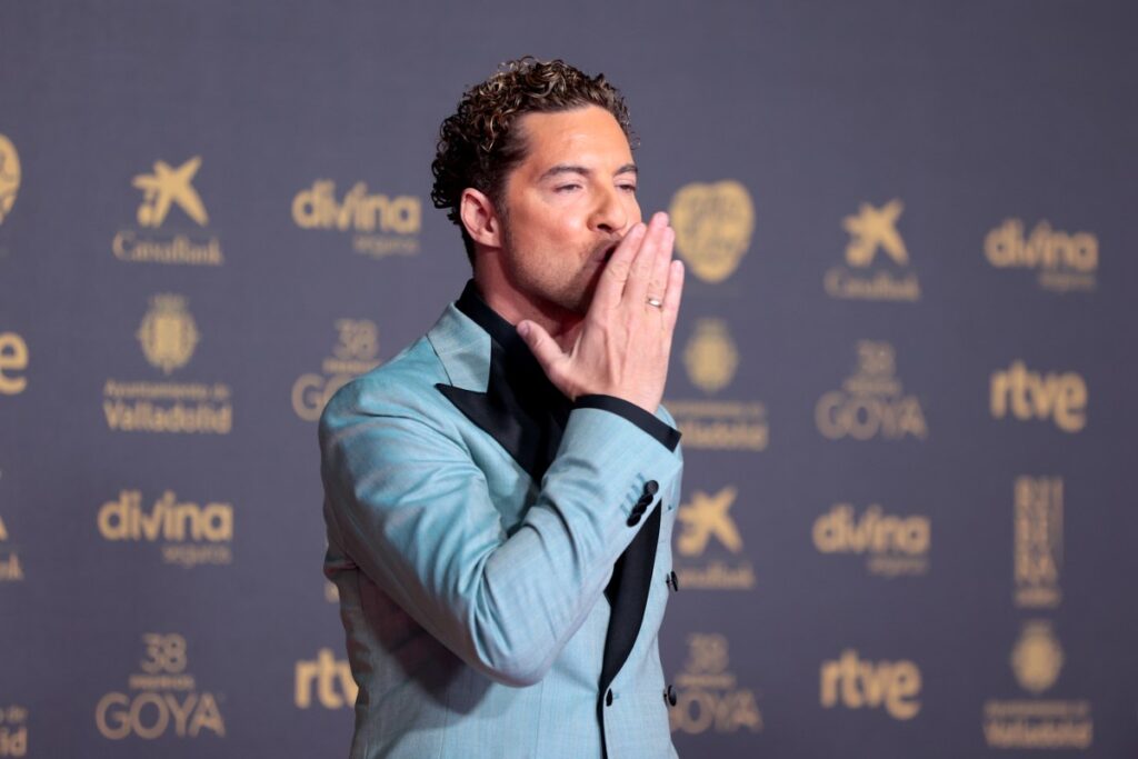 David Bisbal sonríe en el plató de 'Operación Triunfo' como jurado, con micrófono y fondo de escenario iluminado