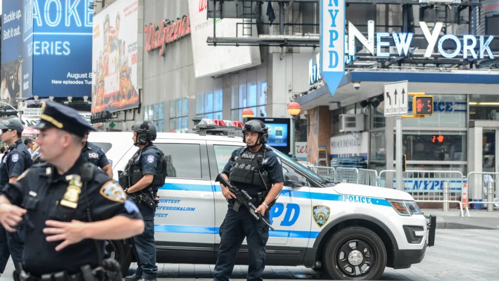 Policías de Nueva York coordinando seguridad en evento masivo con multitudes al fondo