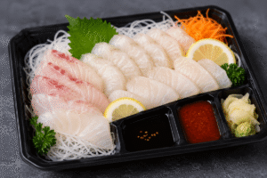 Sashimi coreano en bandeja con sobres de condimentos y etiquetas de alérgenos