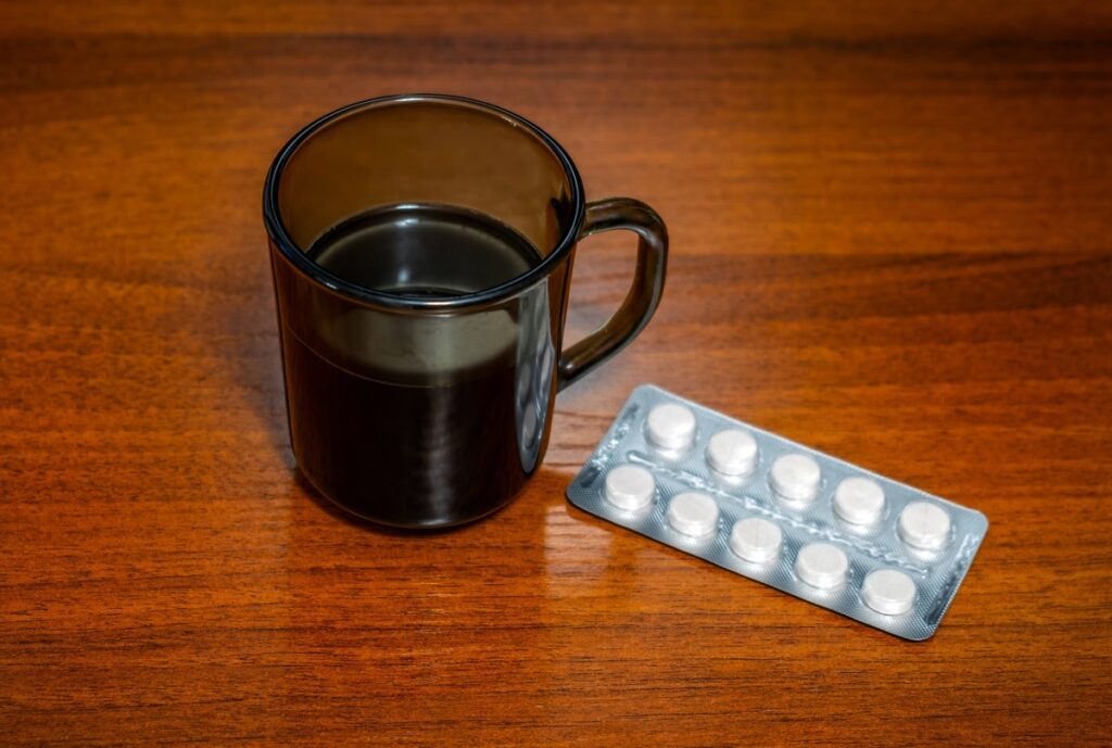 Taza de café junto a pastillas y gráfico de interacciones farmacológicas